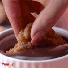 a person is dipping a piece of food into a bowl that says yum up on it