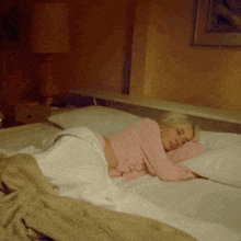 a woman in a pink top is sleeping on a bed