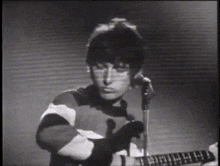 a man is playing a guitar and singing into a microphone