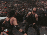 two wrestlers are fighting in a wrestling ring with a crowd watching