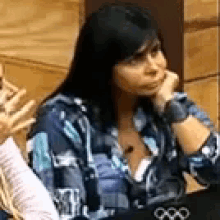a woman is sitting at a table with her hand on her chin and looking at something .