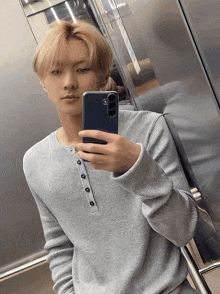 a young man taking a selfie with his phone in an elevator