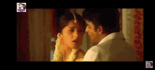 a man and a woman are kissing in a room . the man is wearing a white shirt .
