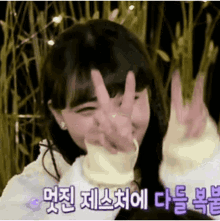a girl is making a peace sign with her hands in a field .