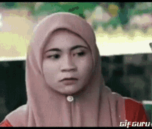 a woman wearing a hijab is making a funny face .