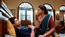 a man is laying on a bed while a woman looks on