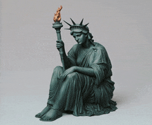 a statue of the statue of liberty is sitting down holding a torch