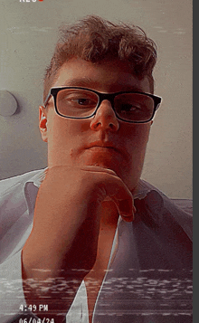 a man wearing glasses and a white shirt has his hand on his chin and the time is 4:49 pm