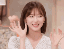 a woman in a white dress is smiling and waving her hand