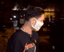 a man wearing a mask and a chain around his neck has a black shirt on