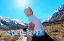 a man in a white shirt is standing in front of a mountain with chinese writing on it