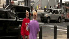 a woman in a purple shirt is walking down a street next to a woman in a red shirt .