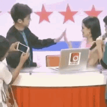 a man and a woman are giving each other a high five while sitting at a table with a laptop .