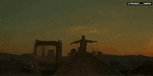 a man is jumping in the air in front of a large fire with the name pranay varma on the bottom left