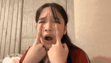 a woman is making a funny face with her hands on her face