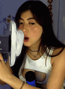 a woman wearing a white tank top with a cut out on the front is playing a game