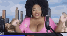 a woman in a pink shirt is sitting in front of a microphone and making a funny face .