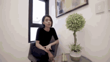 a woman sitting in a chair next to a plant