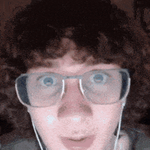 a man with curly hair wearing glasses and headphones