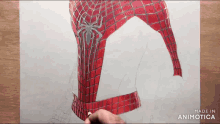 a person is drawing a spiderman costume on a piece of paper