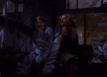 a blurry picture of a man sitting in a dark room with papers flying around him .
