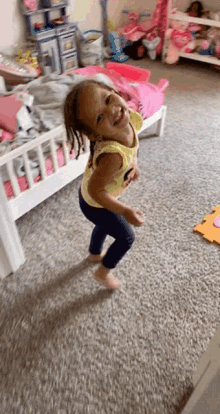 a little girl in a minnie mouse shirt is dancing in a bedroom
