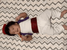 a baby dressed as aladdin is laying on a blanket on a bed .
