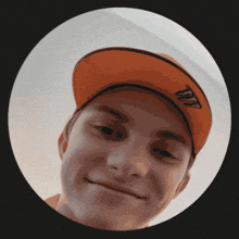 a young man wearing an orange hat with the letter t on it