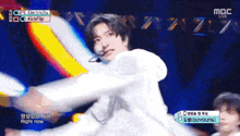 a man in a white shirt is dancing on a stage with a microphone in his mouth .