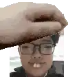 a man wearing glasses and a towel on his head is being touched by a hand .