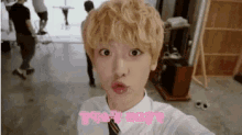 a young man with blonde hair is taking a selfie .