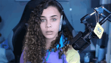 a girl with curly hair is sitting in front of a microphone with a spongebob tag on it