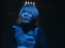a close up of a person 's face with blue hair in a dark room .