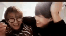 two young men wearing glasses are hugging each other on a screen .