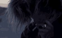 a woman is smoking a cigarette in the dark with a ring on her finger .