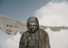 a man wearing a hooded jacket stands in front of a banner with the number 308