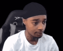 a man wearing a black hat and a white shirt is sitting in a gaming chair .