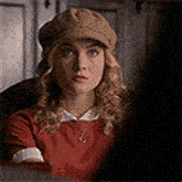 a woman is wearing a hat and a red sweater .