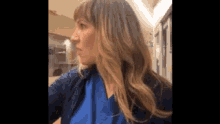 a woman wearing a blue scrub top is standing in a hallway