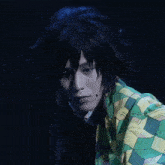 a man with long black hair and a green and yellow jacket