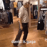an elderly man is dancing in a clothing store with the words david is gaga written on the floor .