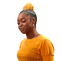 a woman wearing a yellow shirt and earrings looks down