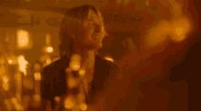 a man with long hair is smiling in a dark room with a blurred background .