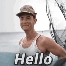 a man wearing a hat and a tank top is standing on a boat and saying `` hello '' .