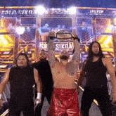 a group of wrestlers are standing in front of a sign that says ' and new ' on it