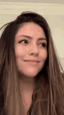 a close up of a woman 's face with long hair and a smile on her face .