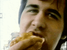 a close up of a man eating a hamburger with his mouth open