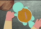 a person is holding a cartoon turtle with a pink object in its shell