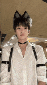 a young man wearing a choker and ears is standing in front of a wooden ceiling