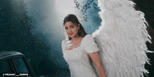 a woman with angel wings is standing in front of a car with the hashtag pranay_varma